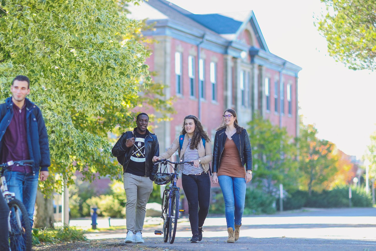 3 students walking on campus in front of Cumming Hall