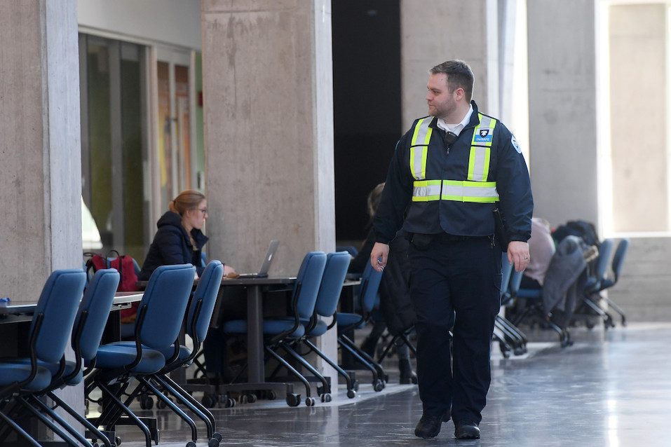 A security guard walks along a brightly lit study hall at Dalhousie University.