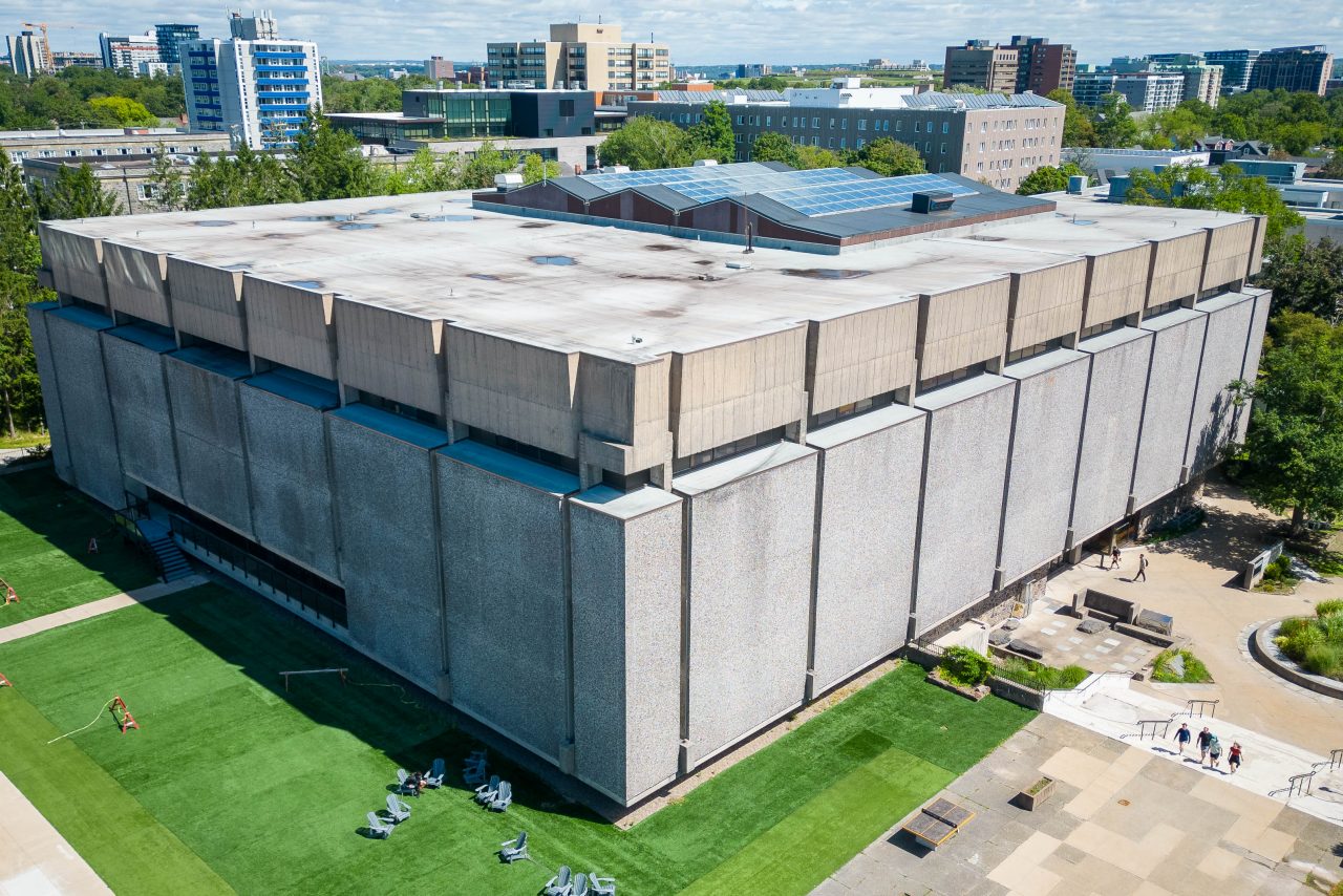 Aerial photograph of Dalhousie's Killam Library; a building with a grey stone exterior surrounded by lawn and courtyard.  