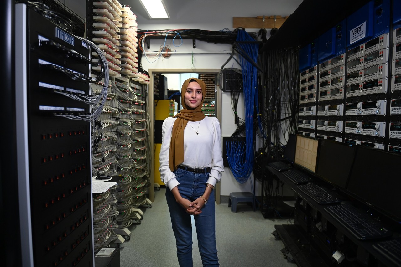 A person stands in the middle of a server room in a computer lab