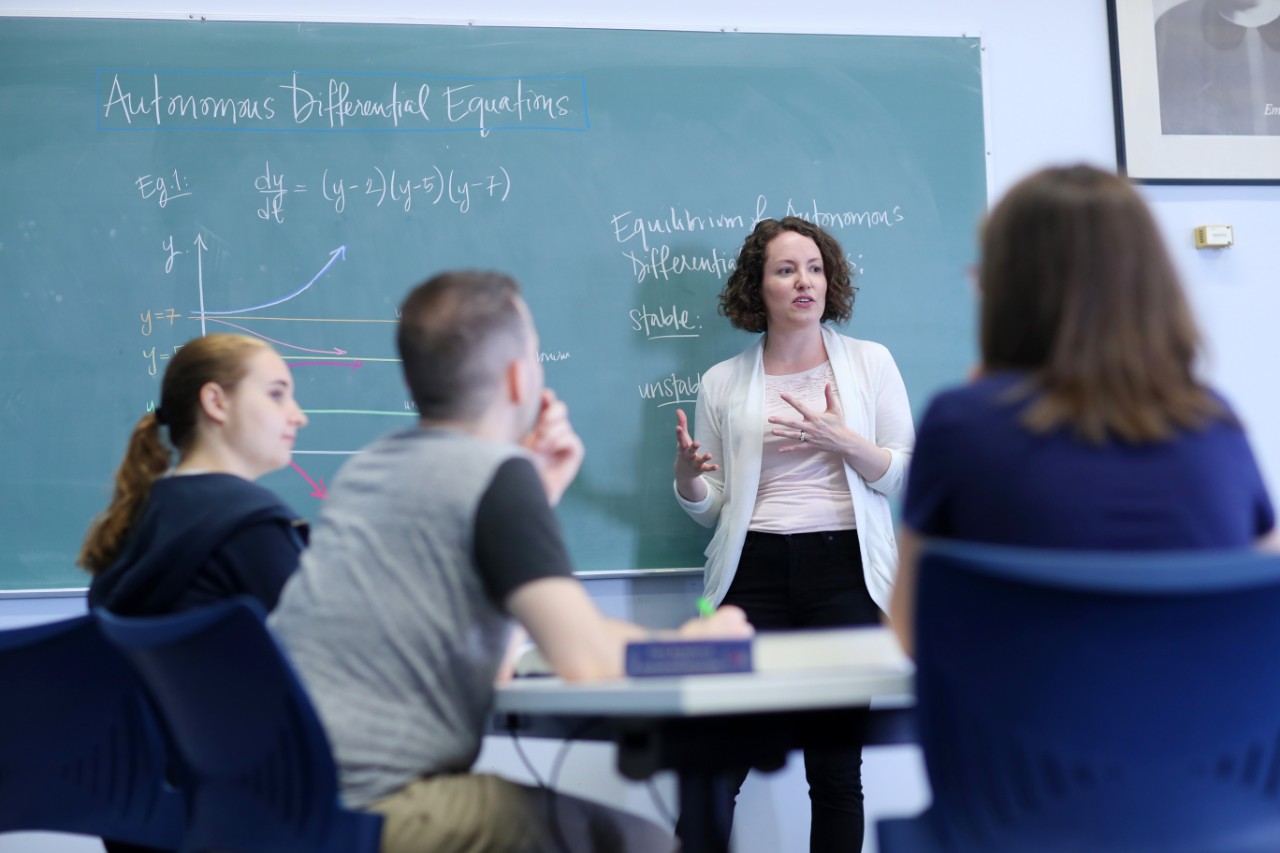 A Dalhousie Science instructor lectures to students in front of a chalk board during a math class