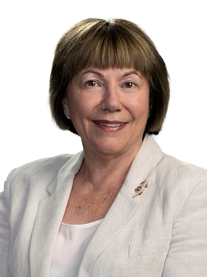 A headshot of a woman with short brown hair wearing a beige blazer