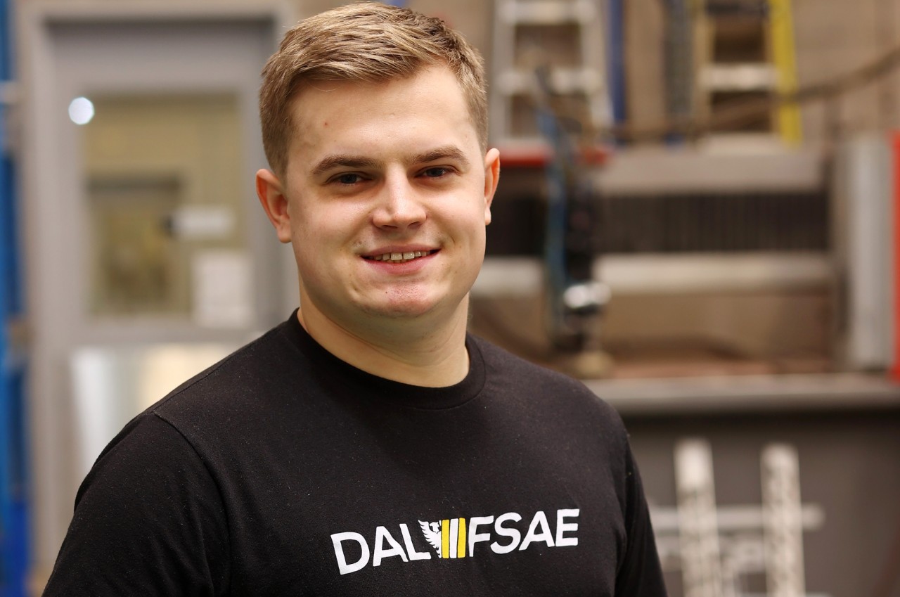 A blonde-haired man wearing a balck t-shirt that says Dal FSAE