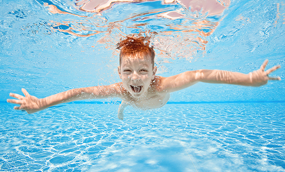 Underwater photo of a happy child swimming in a pool.