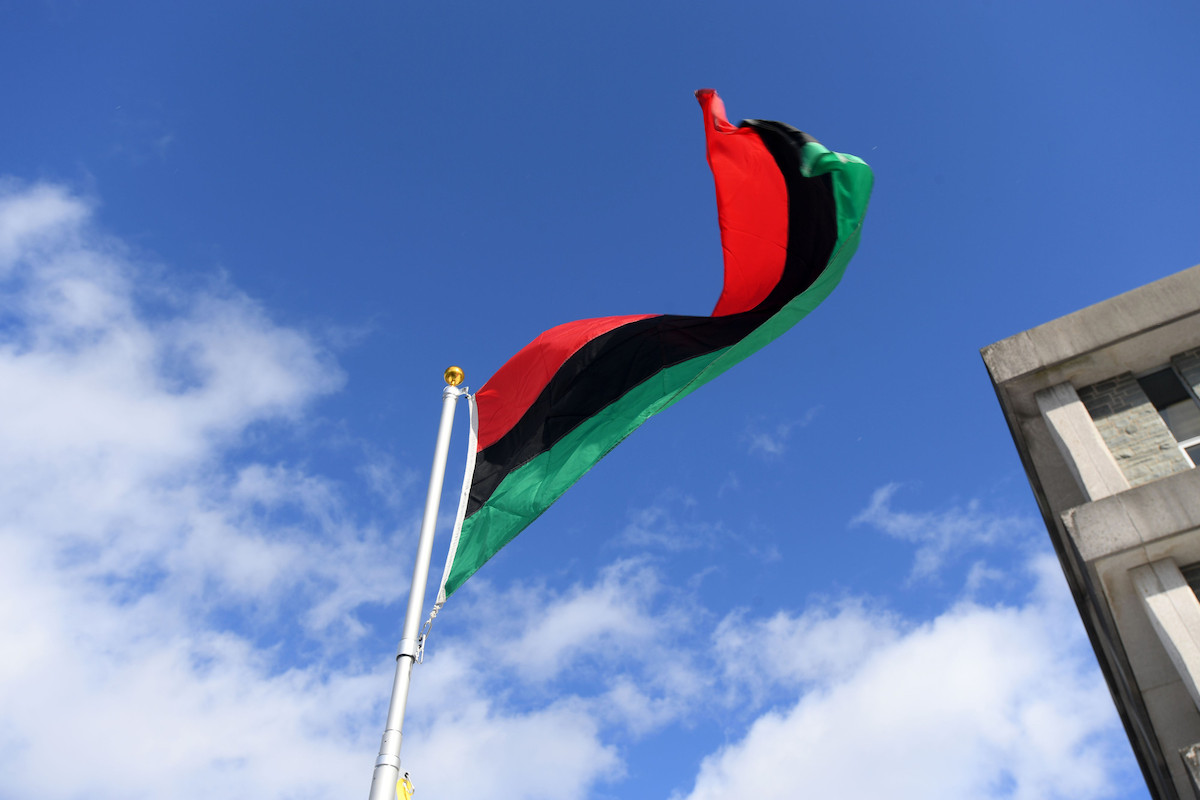 Red, black and green Pan-African flag against blue sky.