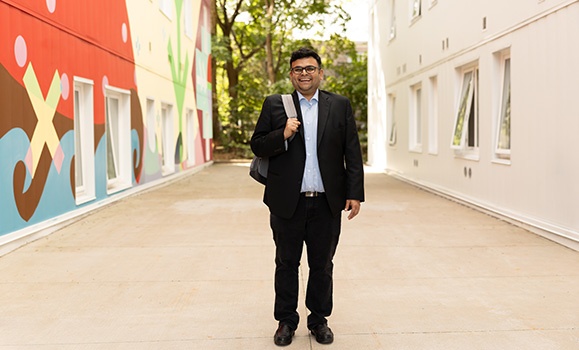 Dr. Raghav Sampangi is wearing a suit walking between two buildings.