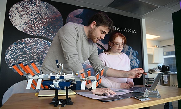Two students are at a desk looking at a computer.