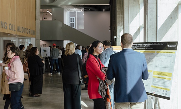 A hallway of poster displays and event participants talking.