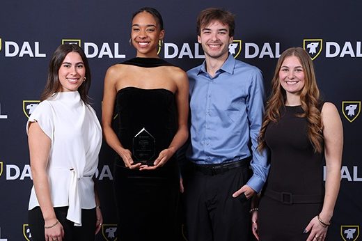 Two cartoon characters are carrying two bags of cash - one with a pounds symbol and one with a dollar sign - on a platform labeled 'for investment in Canada'. A sign behind them points them 'to Canada'. 