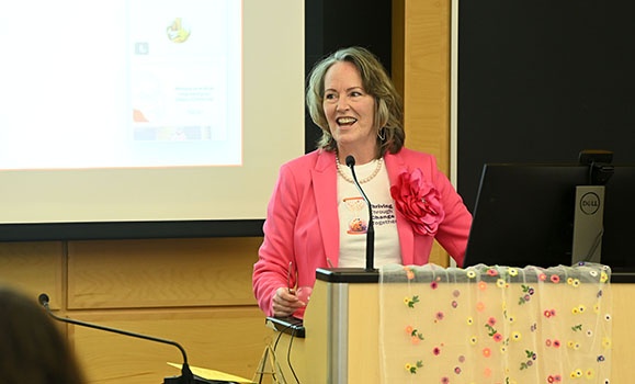 Dr. Shawna O'Hearn is standing at a podium wearing a pink blazer.