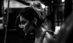 A close up shot of a woman doing a back squat at the gym. The image is in grey scale.