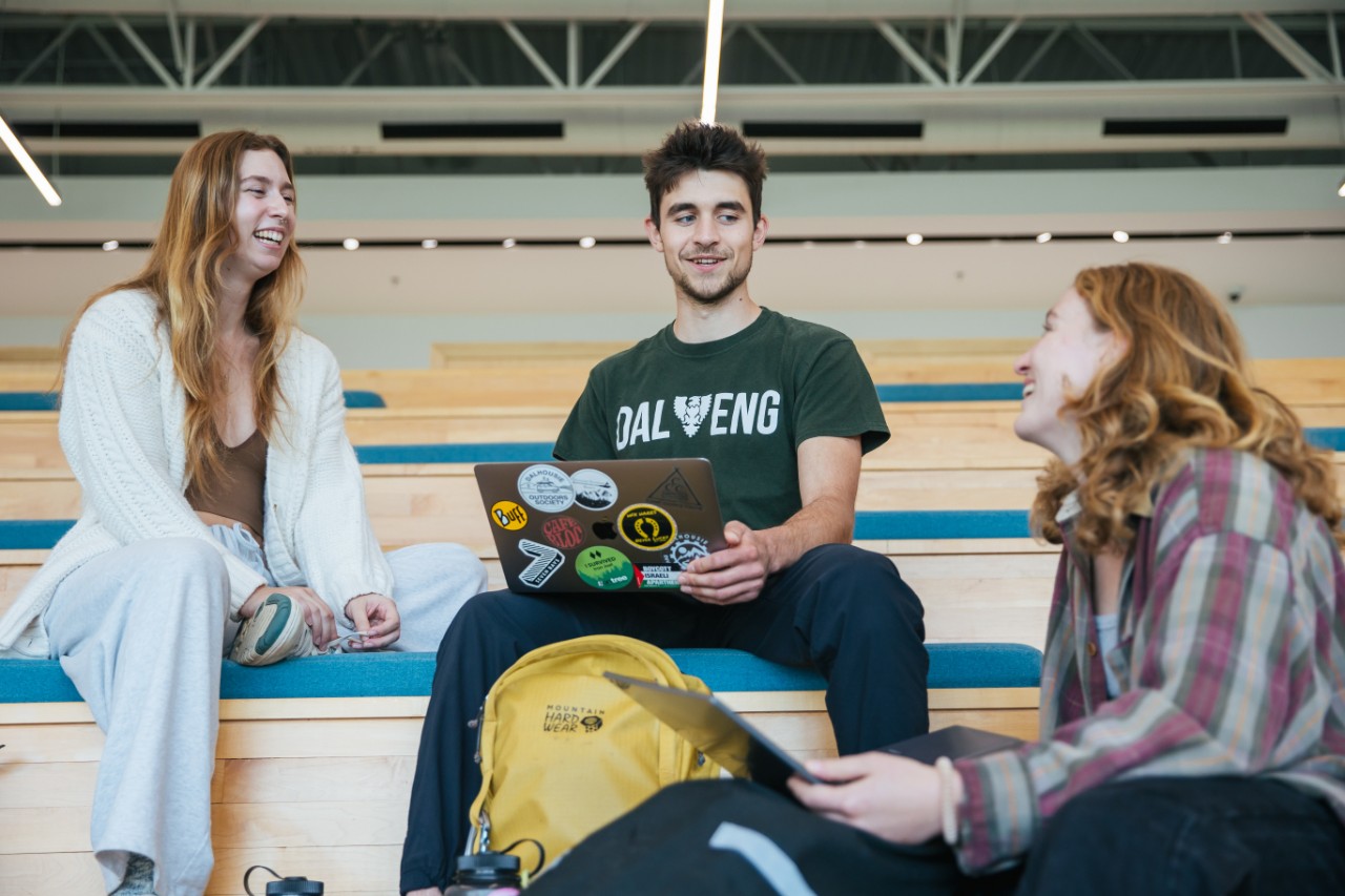 three students sit on steps inside having a conversation