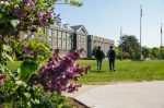 two students walking in Studley Quad by blooming lilacs