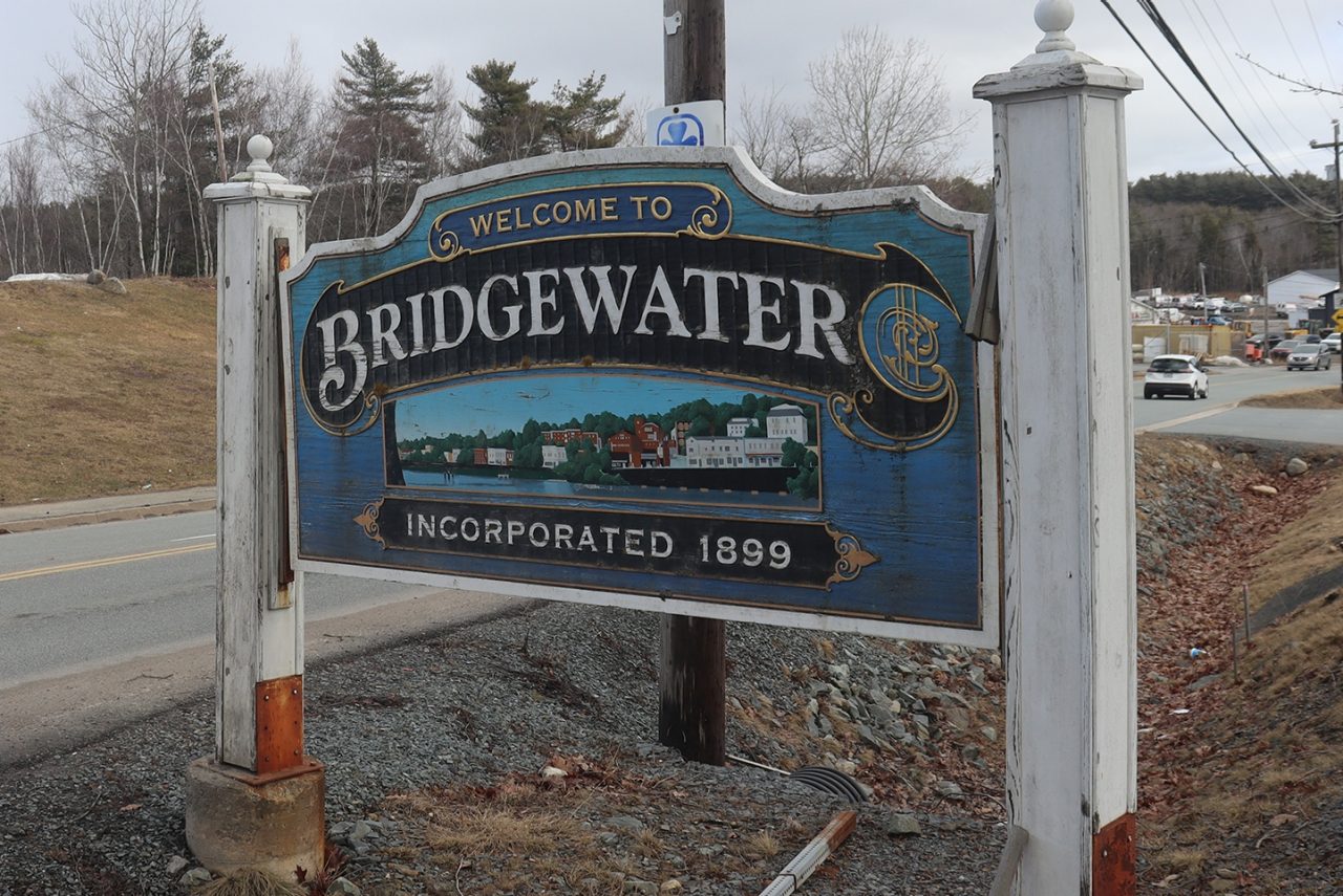 Welcome to Bridgewater sign by a roadside, with cars and buildings in the background.