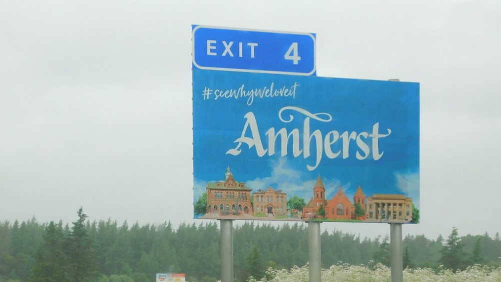 Highway Exit 4 sign for Amherst with town buildings illustrated.