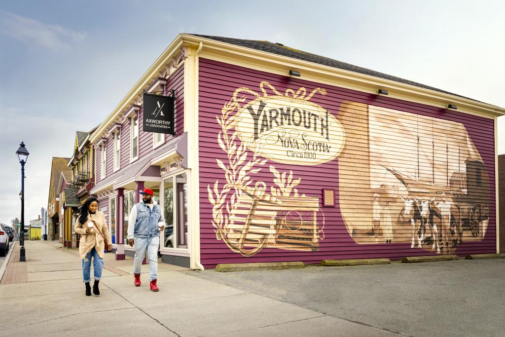 Two people walking on the sidewalk next to a building