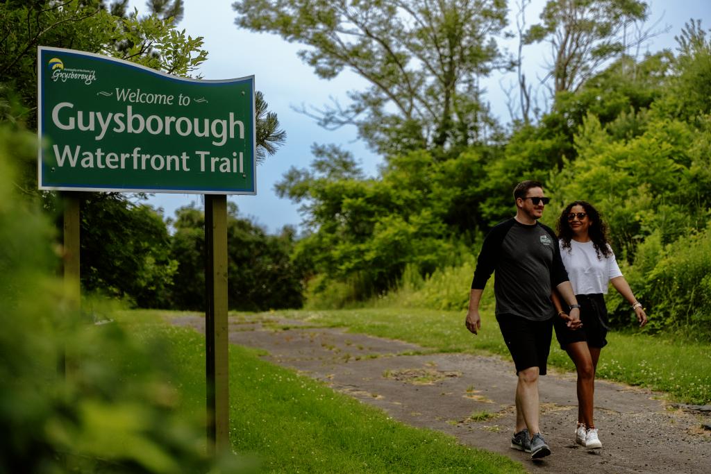 Guysborough sign with two people walking on a trail