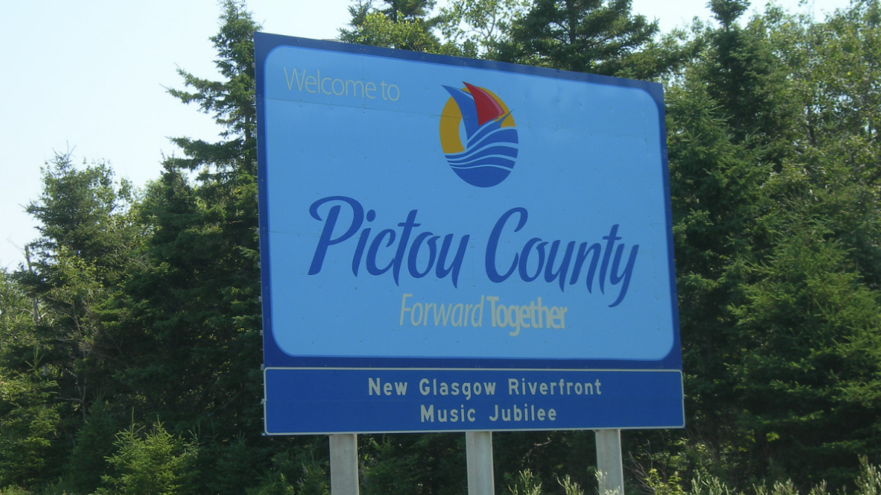 Pictou County sign with sailboat logo, snow, and trees in background