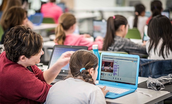Young women sitting at computers learning how to code