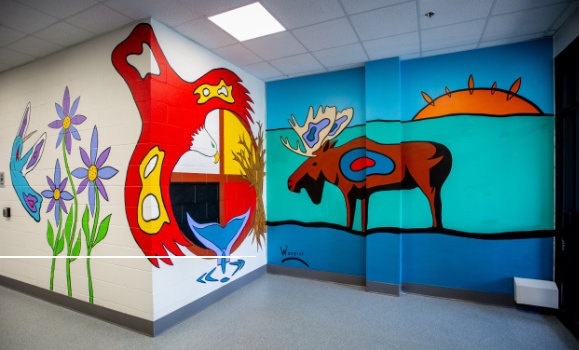 Brightly coloured murals depicting a moose and a bird adorn the walls of a hallway.