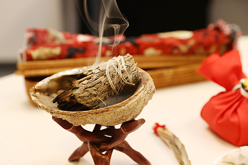 Burning bundle of sage sits in a shell.