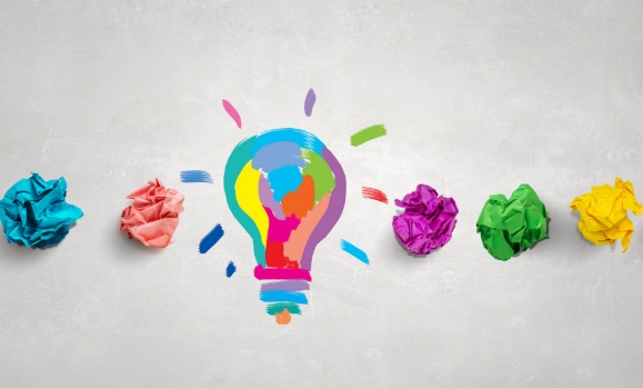 Different coloured pieces of scrunched up paper and a colourful lightbulb in the centre