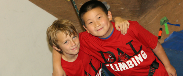 Two children in red Dal shirts with their arms around each other.