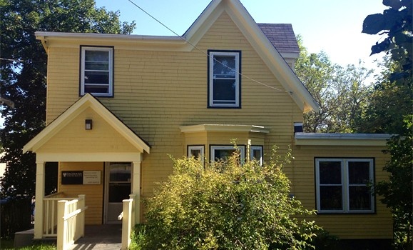 A bright yellow house with a Dalhousie-branded sign saying "South House" on a sunny day.