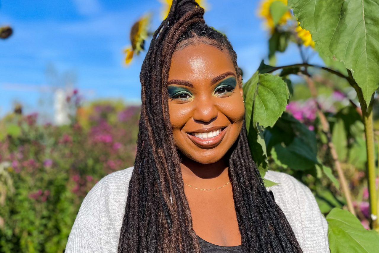 Dr. Kristal Ambrose poses in field with sunflowers