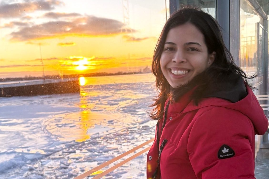 Image of a woman wearing a red parka, standing near a frozen body of water.
