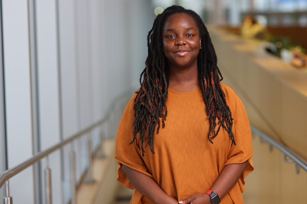 Timi Idris wearing an orange shirt, smiling at the camera.
