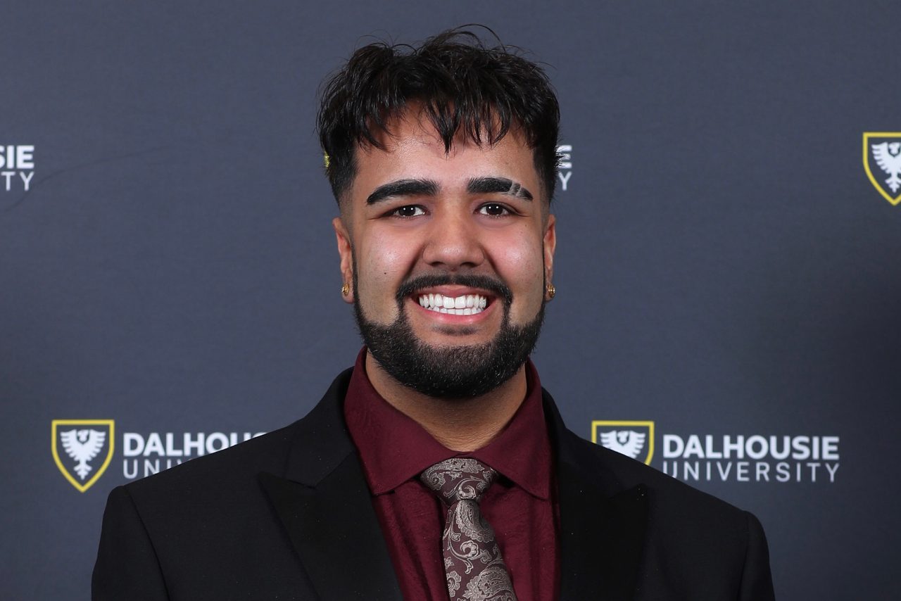 Eshan Arora wearing a suit and tie, smiling.