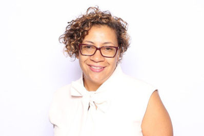 Liza Arnason smiling. She wears a white shirt and glasses.