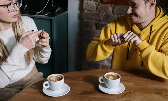 Two people drinking coffees and chatting.