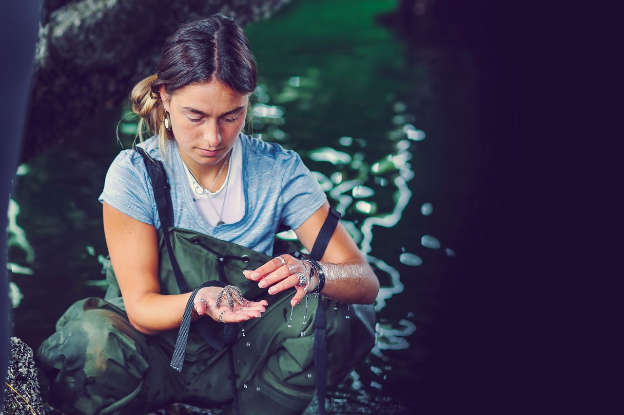 Student in the ocean holding a starfish.