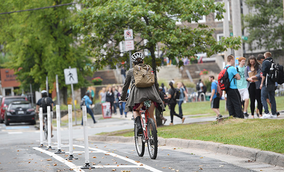 Cyclist travels down a bike lane on campus with sudents nearby.