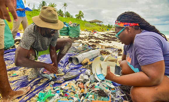 Kristal and others sort through plastic waste on a beach.
