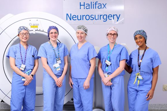 Female team of neurosurgeons poses in blue scrubs.