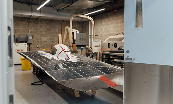 Car covered with solar panels sits in Engineering Lab bay.