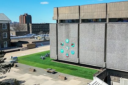 An ariel shot of the brutalist walls of the Killam Memorial Library with seven circular paintings on the left-most panel.