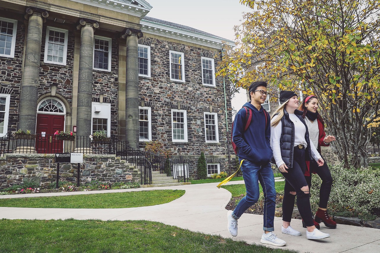 Three students on Studley campus walking in front of the University Club.