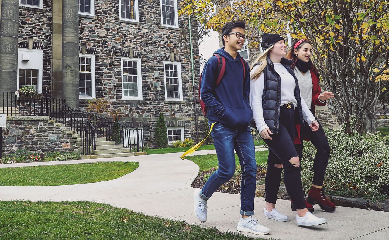 3 students on Studley campus walking in front of the University Club