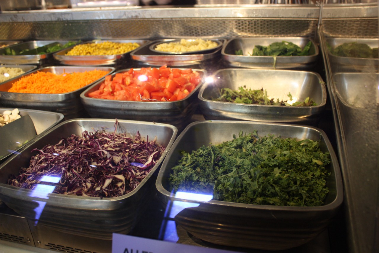 metal bowls of cut vegetables at a salad bar