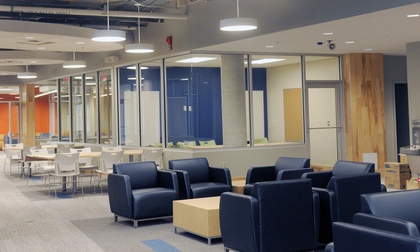 The Wallace McCain Learning Commons with a section of blue comfy chains in front and desks and white chairs behind.