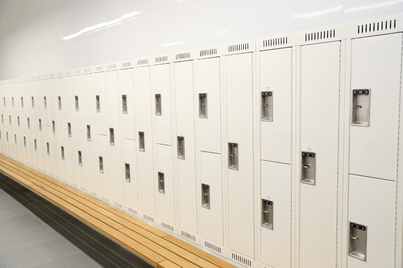 A row of cream coloured lockers and a wooden bench.