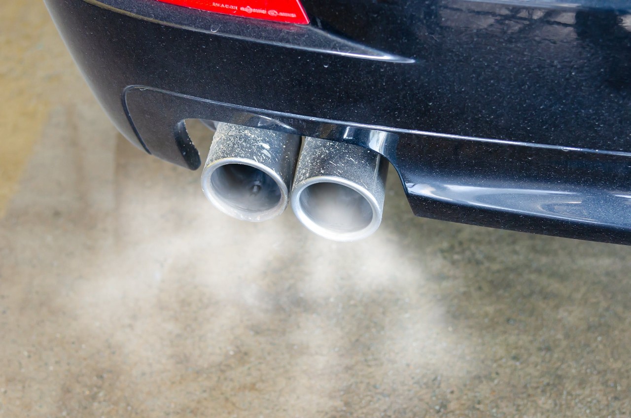 Close-up photo of an idling car's exhaust pipe. 