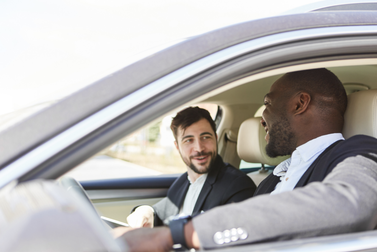 Two office workers sitting in a car and chatting while driving.
