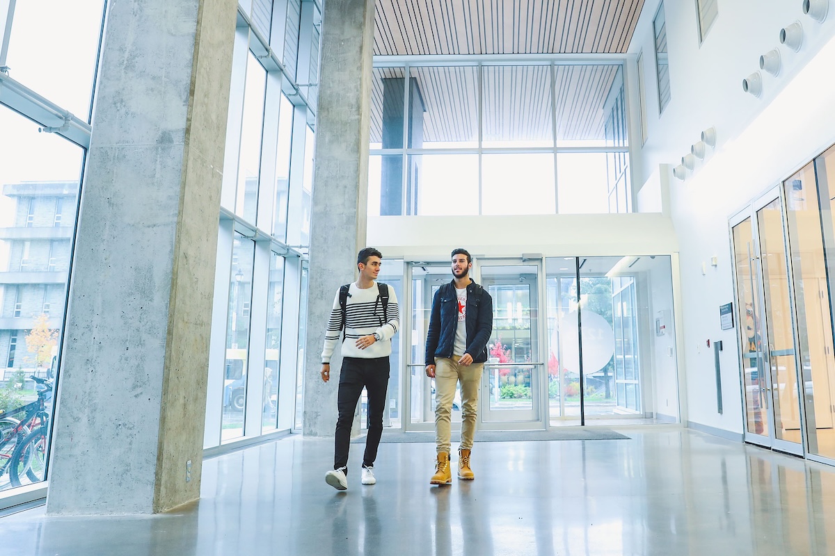 Students walking near the entrance of the building with the Health and Wellness Centre