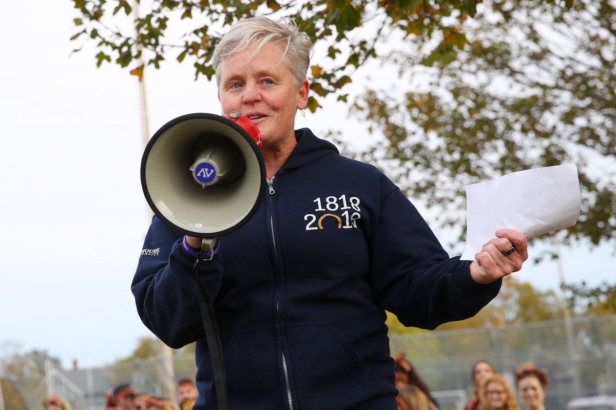 A Dal employee wearing a Dal hoodie speaks through a megaphone to a crowd surrounding them
