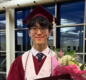 Portrait of Matthew Oh wearing a maroon graduation robe and cap.